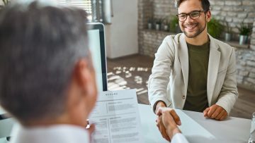 Young happy man shaking hands with a businessman on a job interv